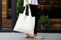 Model hold blank white fabric mockup bag for save environment on street fashion
