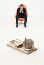 Model home on mouse trap with worried businessman sitting on chair representing increasing real estate rates Royalty Free Stock Photo