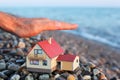 Model of house on beach, Man's hand over house Royalty Free Stock Photo