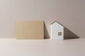 A model of a house on a beige background and a card with nothing written on it Royalty Free Stock Photo