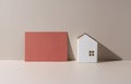 A model of a house on a beige background and a card with nothing written on it Royalty Free Stock Photo