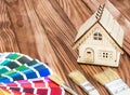 Model of house with brushes and color swatches book. on the wooden table. Home repair and improvement concept Royalty Free Stock Photo