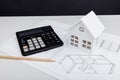 Model of house and calculator on architectural plan. House building costs Royalty Free Stock Photo