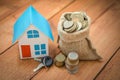 Model house with coins and key on wooden background. The concept of buying and selling a house. Royalty Free Stock Photo