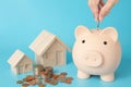Model house, coins stack, Pig piggy, hand holding a coin bank on blue background  for money saving concept Royalty Free Stock Photo
