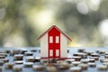 Model of house with coins on table on blurred background. Stack of growing coins, money saving or investing for home loan or real Royalty Free Stock Photo
