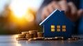 Model house and coins on a table with a warm sunset background Royalty Free Stock Photo