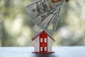 Model of house with dollar bill on table on blurred background. Money saving or investing for home loan or real estate. Investment Royalty Free Stock Photo