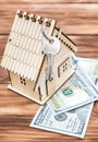 Model of house with dollar bills and key on wooden background Royalty Free Stock Photo