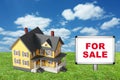 Model house on green grass with for sale sign