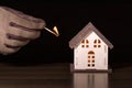Model house and hand in glove with matchstick on a black background. Royalty Free Stock Photo