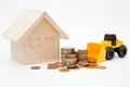 Model house, loader, coins stack on white background for money saving concept