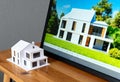 Model house with modern design displayed next to digital render on screen Royalty Free Stock Photo