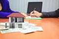 Model house on money and Businessman signing documents on the table, New home and real estate concept