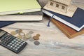 Home savings, budget concept. Model house, notepad, calculator and coins on wooden office table Royalty Free Stock Photo