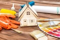 Model of house with paint roller, brushes and color swatches book on the table. Home improvement and repairing concept Royalty Free Stock Photo