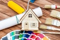 Model of house with paint roller, brushes and color swatches book on the table. Home improvement and repairing concept. Top view Royalty Free Stock Photo