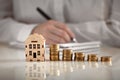 Model house and pile of coins on the table close up, family budget, mortgage, banking and brokerage concept, financial consulting,