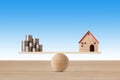 Model house on seesaw balancing with stacking coins money on blue background. Property investment and home mortgage financial real Royalty Free Stock Photo