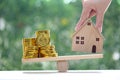 Model house with stack of gold coins money on wood scale seesaw with natural green background,Business investment and real estate Royalty Free Stock Photo