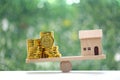 Model house with stack of gold coins money on wood scale seesaw with natural green background,Business investment and real estate Royalty Free Stock Photo