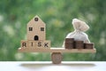 Model house with wording risk and money bag on wood scale seesaw on natural green background, Business investment and Risk