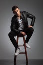 Model in leather jacket posing seated in studio while resting Royalty Free Stock Photo