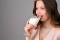 Model licking milk from a wine glass. Close up. Gray background