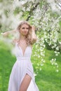 Model in long white dress in blossoming park. Royalty Free Stock Photo
