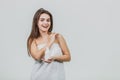 Model look is a beautiful young twin in a white terry towel. Applying a body lotion on her shoulder and smiling while Royalty Free Stock Photo