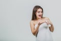 Model look is a beautiful young twin in a white terry towel. Applying a body lotion on her shoulder and smiling while Royalty Free Stock Photo