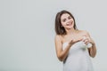 Model look is a beautiful young twin in a white terry towel. Applying a body lotion on her shoulder and smiling while Royalty Free Stock Photo