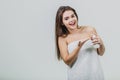 Model look is a beautiful young twin in a white terry towel. Applying a body lotion on her shoulder and smiling while Royalty Free Stock Photo