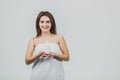 Model look is a beautiful young twin in a white terry towel. Applying a body lotion on her shoulder and smiling while Royalty Free Stock Photo