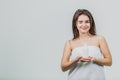 Model look is a beautiful young twin in a white terry towel. Applying a body lotion on her shoulder and smiling while Royalty Free Stock Photo