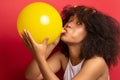 Model with a lush hairstyle inflates a balloon