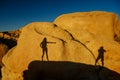 A model and photographer work together in nature, and their shadows appears on a giant rock in the Joshua Tree National Park, Royalty Free Stock Photo