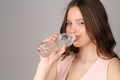 Model in pink top drinking water. Close up. Gray background