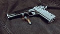 Model 1911 pistol and three cartridges (.45 ACP) on a black denim background Royalty Free Stock Photo