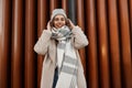 Model of a positive young woman with a beautiful smile in fashionable faux fur coat in a knitted stylish hat with a woolen plaid Royalty Free Stock Photo
