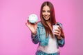 Model positive young woman in stylish denim jacket with cup of tea or coffee posing with donut in mask near the glamorous pink Royalty Free Stock Photo