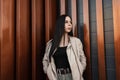 Model pretty young modern woman in youth stylish casual spring clothes stands near vintage metal wall on the street. Beautiful