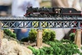 Model railroad. Old locomotive on an iron bridge.