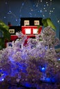 Model of a red brick house in a thicket of lilacs with illumination from a led garland Royalty Free Stock Photo