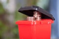 A model of a red trash can with dollar coins coming out of the lid.The Chinese characters on the trash can mean`Harmful refuse`and