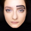 Model`s face with open eyes model looks at camera around eyebrow model has black brow paste applied before coloring and correctio Royalty Free Stock Photo