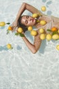 Model`s Portrait In Pool With Citrus. Beautiful Girl Floating On Water With Fresh Tropical Fruit At SPA.