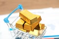 Model shopping cart filled with gold bars