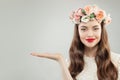 Model Showing Empty Open Hand with Copy Space on White Background. Pretty Girl with Healthy Skin, Long Hair, Makeup and Flowers