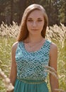 Beautiful,nice,pretty girl with green eyes,cute face,long hair stand in sunny,yellow field with ears,wheet,crops in summer day. Royalty Free Stock Photo